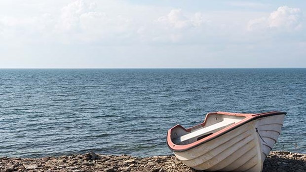 Liten båt som ligger på strandkant